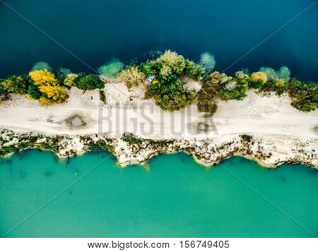 Aerial view - narrow strip of sandy shore and green and blue water, top view