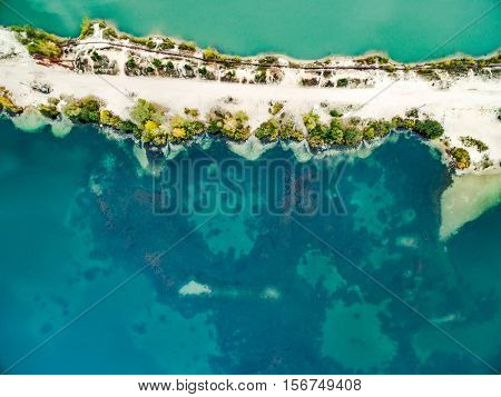 Aerial view - narrow strip of sandy shore and green and blue water, top view