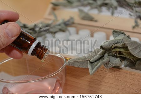 From brown glass vial drops something into another liquid - close-up
