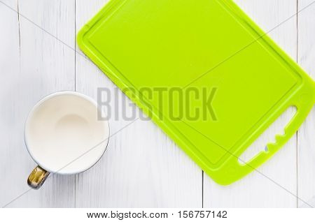 cup with a green cutting board on a white table top