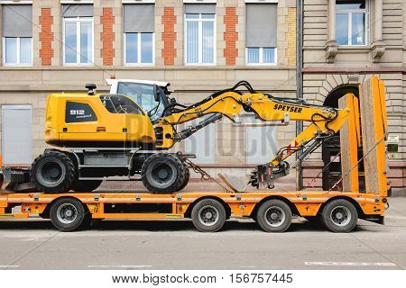 STRASBOURG FRANCE - MAY 18 2016: Liebherr 912 compact excavator on transportation trailer in urban environment with luxury apartment office historic building behind