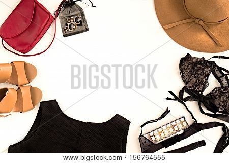 Flat lay of elegant feminine clothing and accessories. Fashion little black dress lace bra perfumes nude shoes marsala bag and hat. Copy space for text