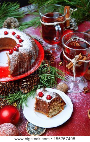 Piece of christmas pudding cake on white saucer decorated with berries sprinkled with sugar powder. Traditional christmal food.