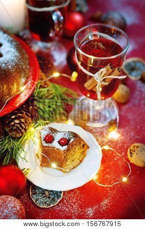 Christmas table setting. Bundt cake pudding sprinkled with sugar powder decorated with red currant and mulled wine.