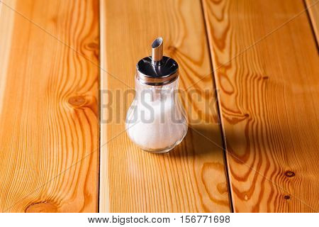 batcher metal glass with granulated sugar on wooden table.