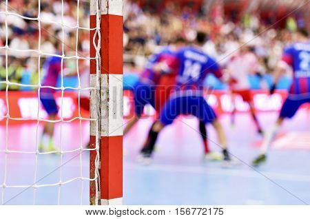 Handball match scene with goalpost and players in the background
