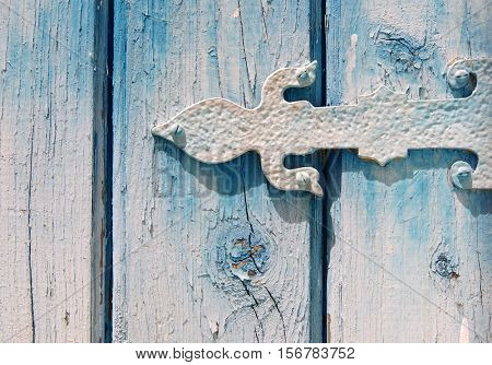 Detail of a painted old hinge on a cracked wooden door