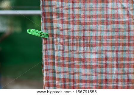 Plastic clothespin green pin and chintz drying on washing line