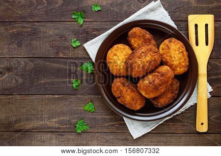 Meat mini-rolls (cutlet) with boiled egg in a clay bowl on dark wooden background. The top view.