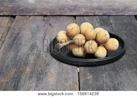 southern langsat Wollongong on a black plate in wooden background tropical fruit at South of Thailand