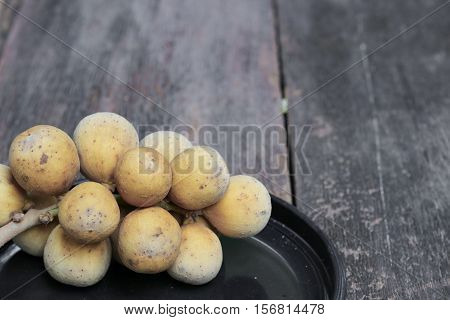 southern langsat Wollongong on a black plate in wooden background tropical fruit at South of Thailand