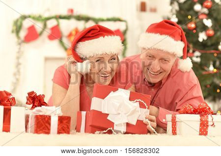 Portrait of happy senior couple in Santa hats celibrating Christmas or New Year at home