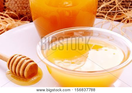 honey dripper and jar of honey and honeycomb as background