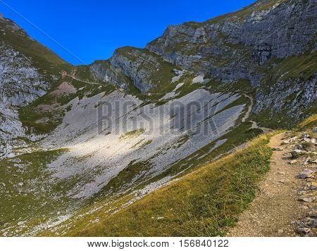 Narrow hiking path with spacious rocky slope down mountain at Hochiss, Brandenberg Alps in Tyrol, Austria