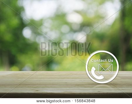 Telephone and mail icon button on wooden table over blur green tree background Contact us concept