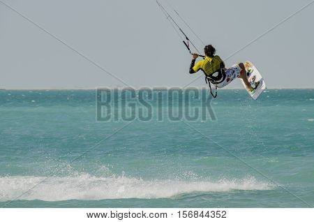 Kite surfer catching air over turquoise blue sea