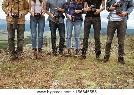 Group of travel photographers stands on line with cameras in hands. Team and teamwork concept