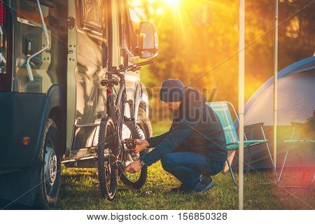 Fall Camping Time. Motorhome and Tent Camping. Men Preparing His Mountain Bike For a Trip.