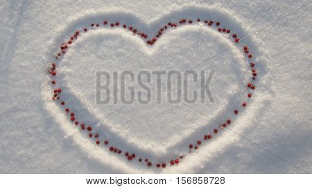 Heart of red berries in the snow