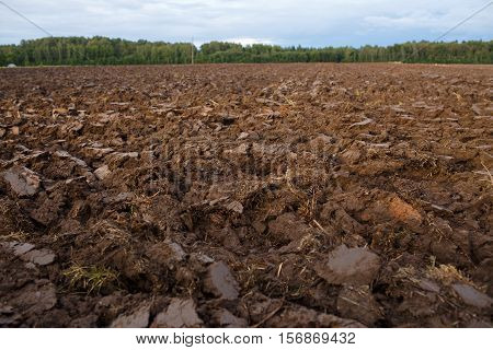 plowed field with tractor traces in spring time, farm soil background.