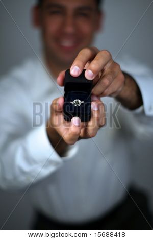 A man proposing and holding up an engagement ring