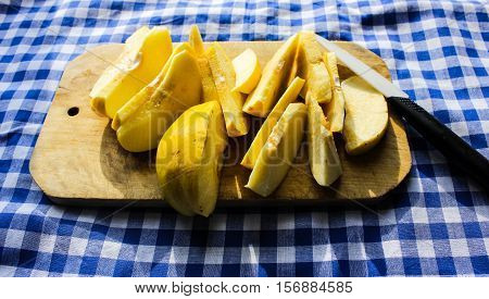 chopped into pieces quince. on a board with nozhom.skatert blue in a cage