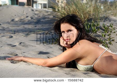 Bela modelo na praia deitado na areia