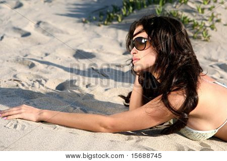 Beautiful model on the beach laying in the sand