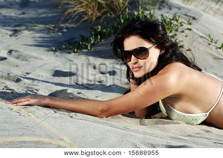 Bela modelo na praia deitado na areia