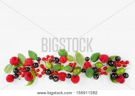 Various fresh summer berries. Ripe raspberries currants gooseberries mint and basil leaves. Berries on white background. Top view