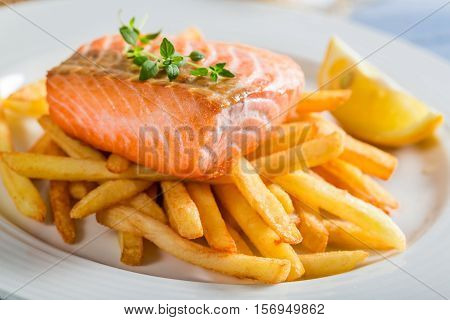 Tasty French Fries With Salmon Served On Plate With Lemon