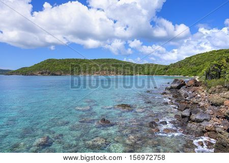 Clear turquoise blue water and rocky shoreline becoming sandy beach in the distance at Punta Soldado Beach on Puerto Rico island of Isla Culebra
