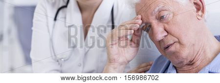 Saddened older man is sitting worry and female doctor trying to comfort him