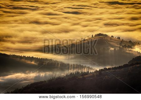 Sunrise landscape of foggy and cloudy mountain valley. Majestic sunrise