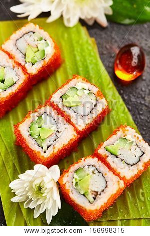 California Maki Sushi with Masago - Roll made of Crab Meat, Avocado, Cucumber, Japanese Mayonnaise inside. Masago (smelt roe) outside. Sushi Food and Natural Flower Concept