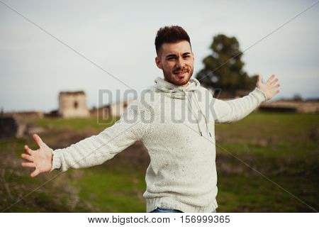 Strong guy open his arms in the meadow. 