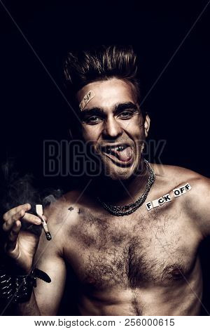 Antisocial behavior, bad habits. Portrait of a bad boy smoking cigarette. Rocker, punk.