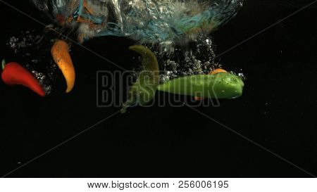 Paprika falling into water on black background. Bright high quality video. Shot 120 frames per second on BlackMagic URSA camera.