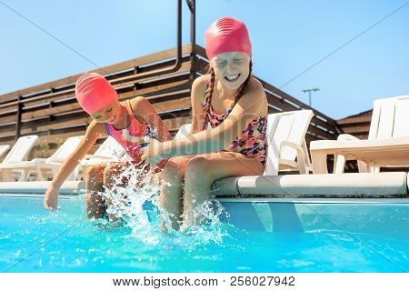 The Portrait Of Happy Smiling Beautiful Teen Girls At The Swimming Pool. Little Child At Blue Wate. 