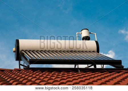 Solar Water Heater Boiler Close Up Shot On Residentual House Rooftop, Blue Sky Background.