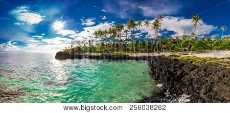 Beach with coral reef on south side of Upolu framed by palm leaves, Samoa Islands