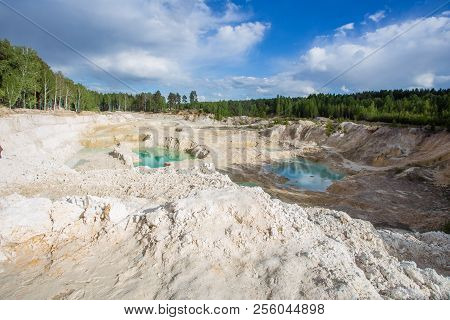 Kaolin clay quarry open pit at summer day with blue water