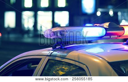 Blue Light Flasher Atop Of A Police Car. City Lights On The Background.