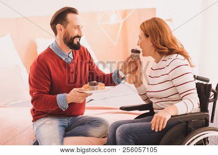 Positive Man Feeding His Wife With Cupcakes