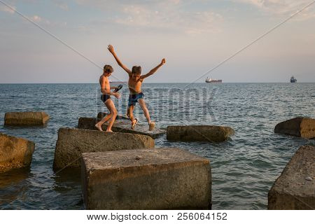 Gizelle-dere Village, Russia, August 07, 2018: Two Friends Are Playing On The Beach, Jumping On Conc