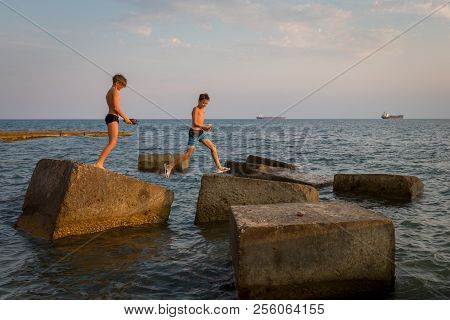 Gizelle-dere Village, Russia, August 07, 2018: Boys Are Jumping From One Concrete Block To Another B