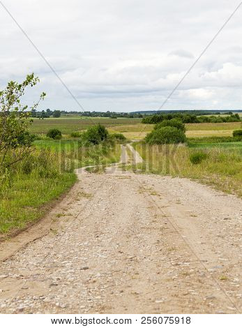 Sandy With Gravel Car Road Through The Field, Cloudy Weather