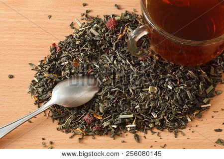 Background With Green Tea. Cup With Tea And Dried Green Tea Leaves On The Table. Spilled Tea Leaves 
