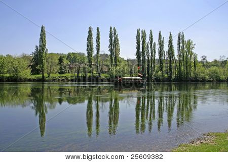 boat going down river and tree reflection in water