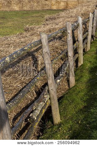 Stacks Of Old Last Year Straw Fenced Off By A Primitive Wooden Fence